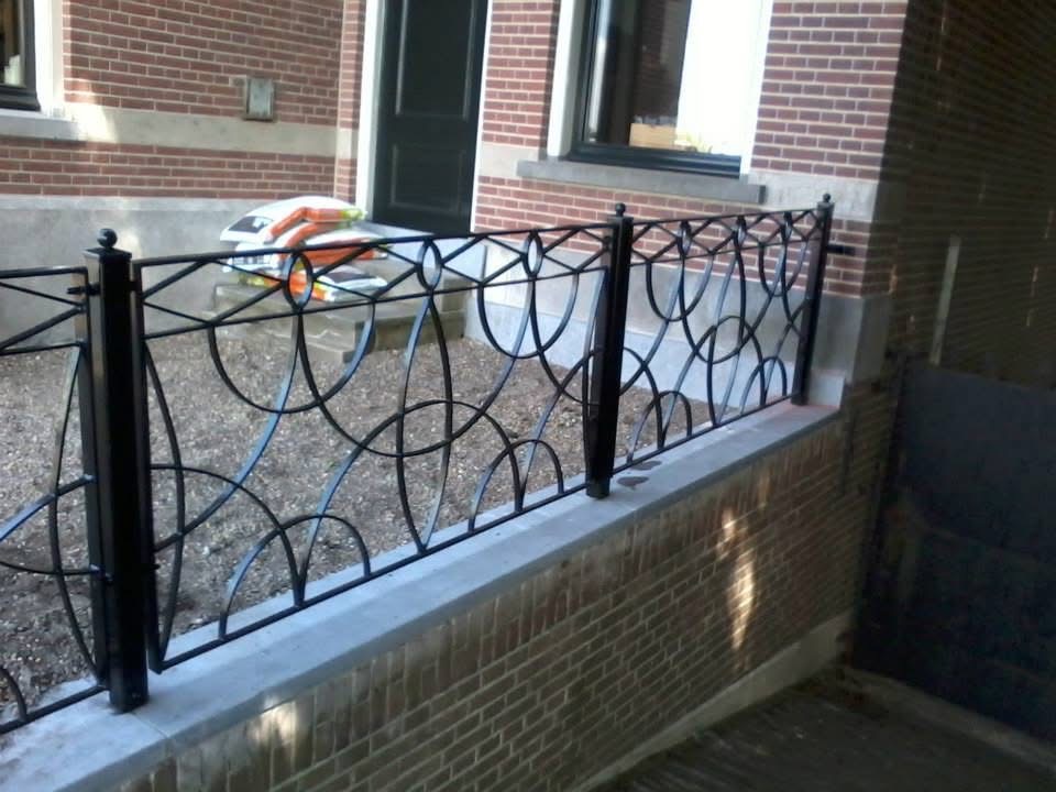 Gerestaureerd muurhek met klassiek krullenpatroon op gemetselde tuinmuur